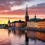 A stunning view of Stockholm's Gamla Stan at sunset, reflecting in the water, with vibrant colors.